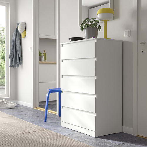 Cómoda blanca LILLBERGET en el espacio de estar con taburete azul, lámpara amarilla y planta verde encima, junto a una puerta.