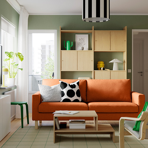 Sala de estar acogedora con sofá naranja quemado, estantería y detalles verdes.