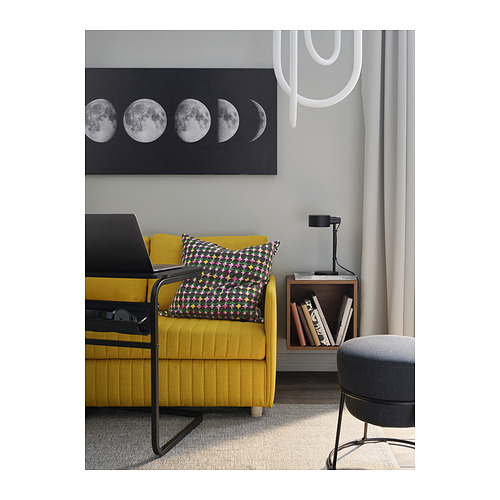 Silla mostaza amarilla brillante con almohada estampada multicolor cerca de mesita de noche negra y cortina gris.