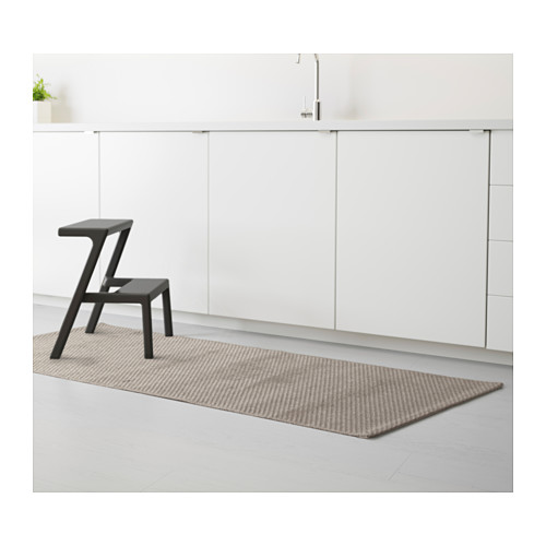 Cocina moderna con armarios blancos y suelos de madera clara. Taburete negro sobre alfombra de corredor estampada, adecuado para mucho tráfico.