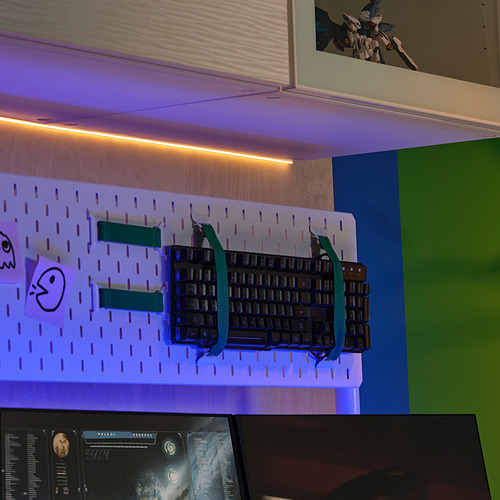 Tiras de luces LED sobre el soporte del teclado con correas verde azulado, monitor debajo, configuración del espacio de trabajo.