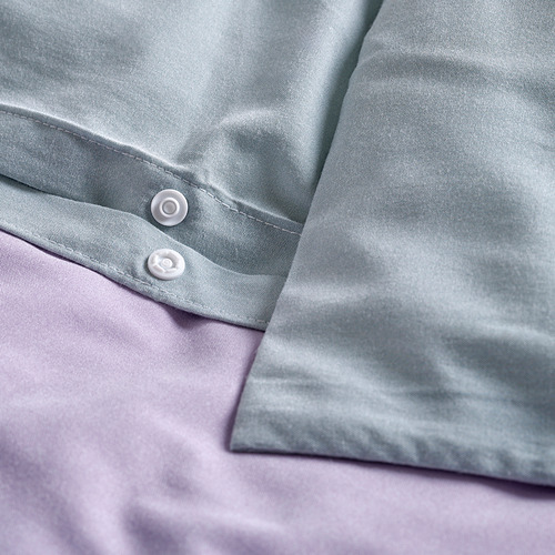 Edredón gris claro con pliegue, mostrando detalles de cierre tipo press bolt.