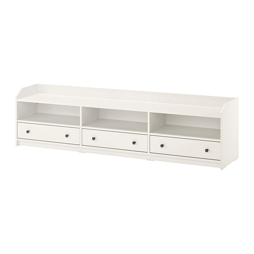 Un mueble de TV blanco IKEA HAUGA con tres cajones y compartimentos abiertos, diseñado para uso doméstico, que ofrece tanto almacenamiento como gestión de cables.