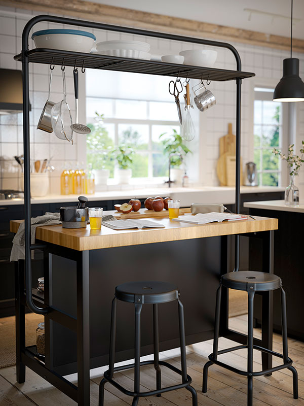 A VADHOLMA kitchen island with a SMÅÄTA chopping board and a VARGAGEN glassware set, an IKEA 365+ frying pan with lid, and a RÖRT spoon.