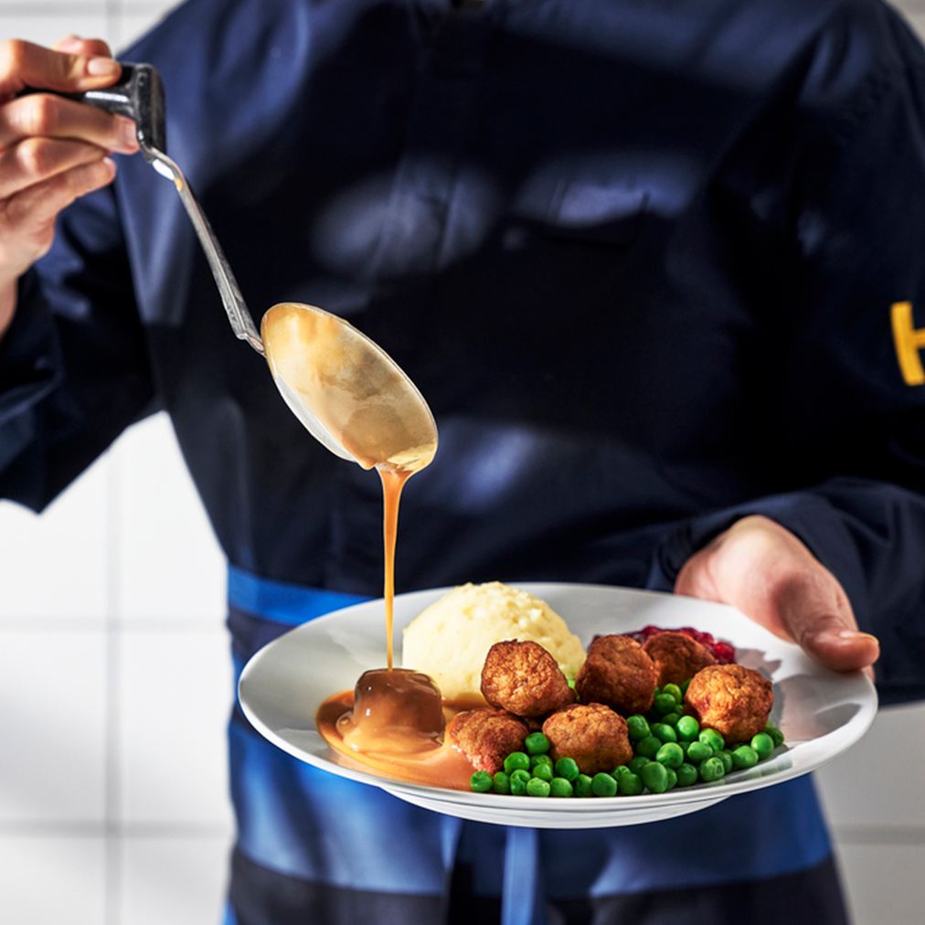Chef bañando albóndigas de IKEA con salsa.