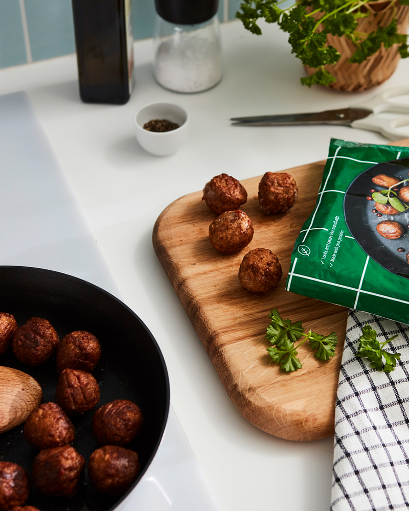 Albóndigas de proteína vegetal de IKEA sobre un sartén y una tabla de madera.