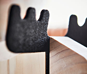 Dos piezas de madera unidas con espuma negra entre ellas.