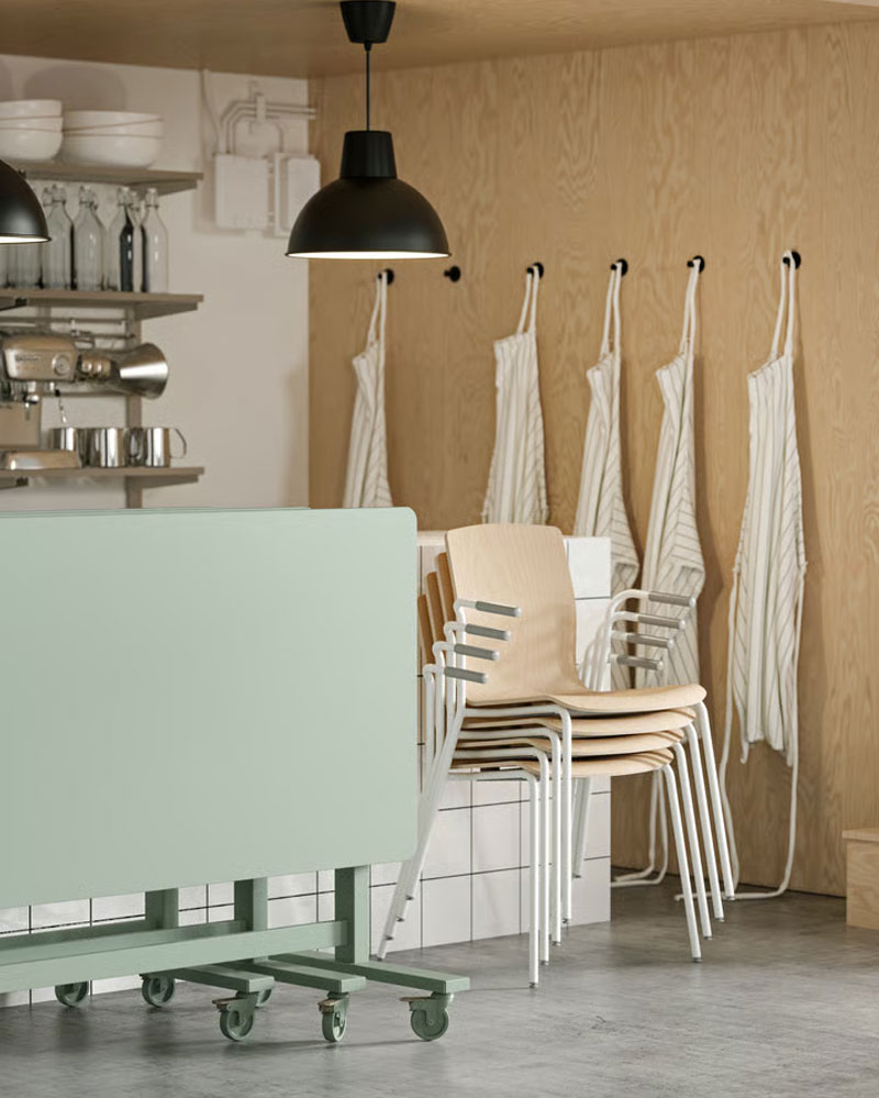 Four LÄKTARE conference chairs in birch veneer/white stacked against a counter, with green folded MITTZON tables beside them