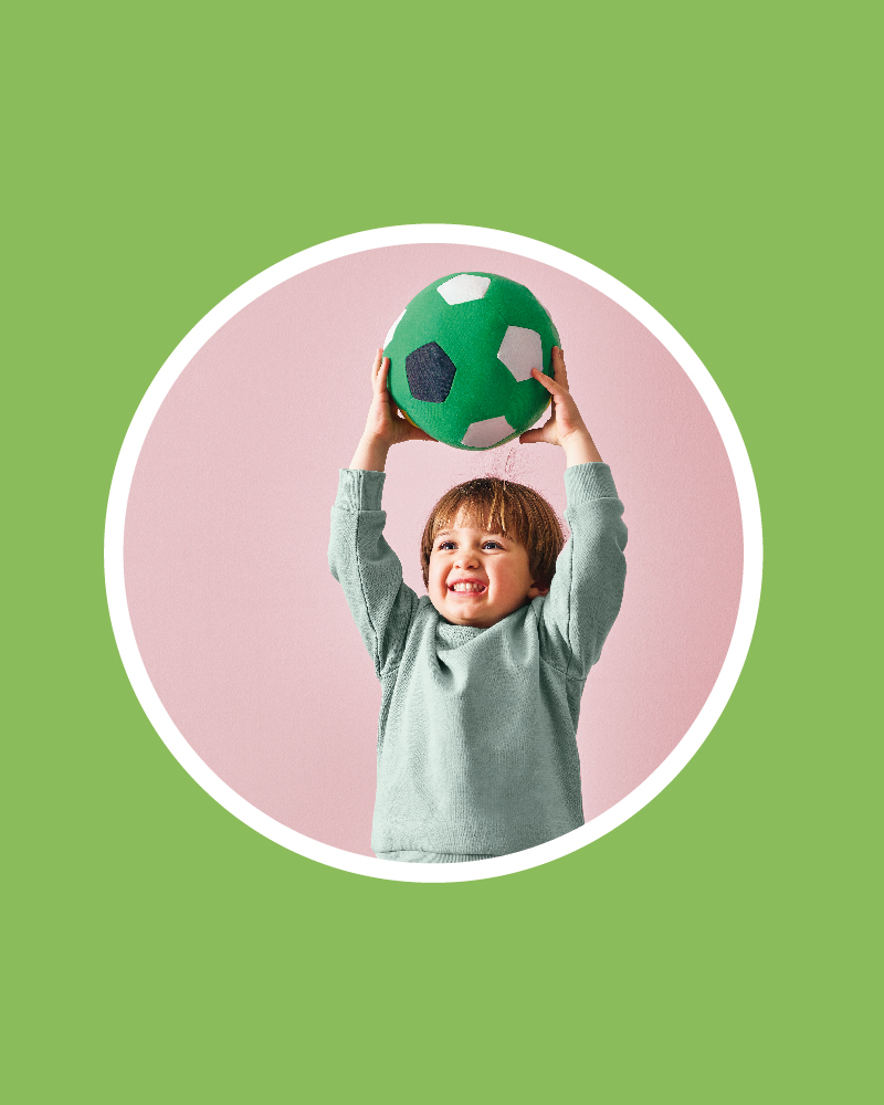 un niño alzando una pelota de peluche verde