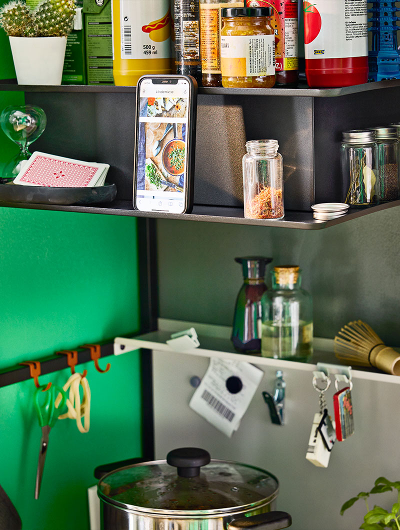 Black VIGGBO wall mounted extractor hood with in-built shelf in compact ÄSPINGE kitchenette stocked with food