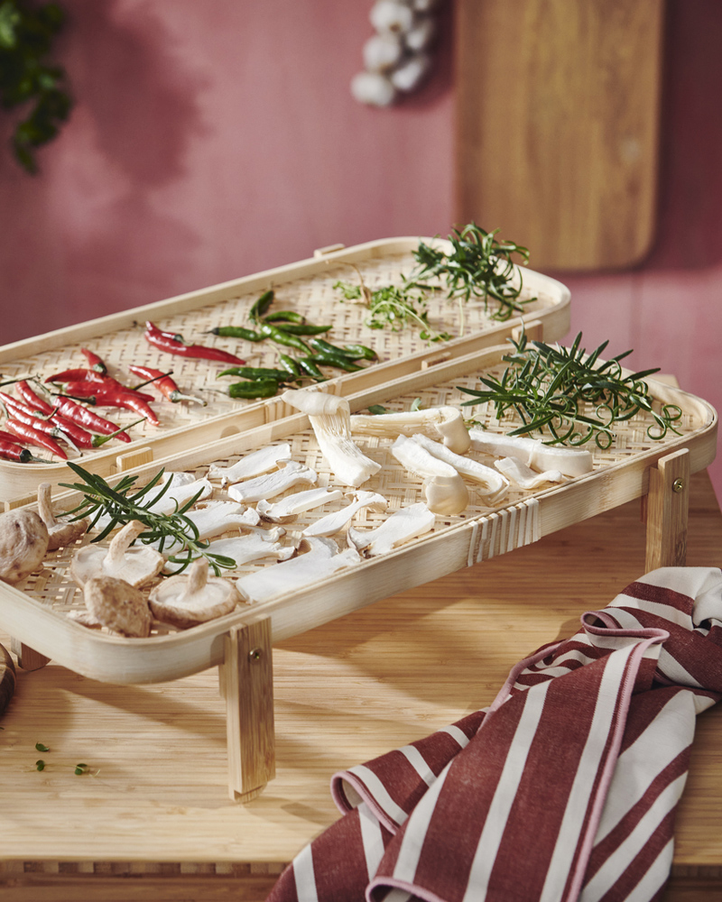 Un tarro de cristal transparente KÖSSEBÄR con tapa, lleno de coliflor y otras verduras, descansa sobre una encimera de madera.