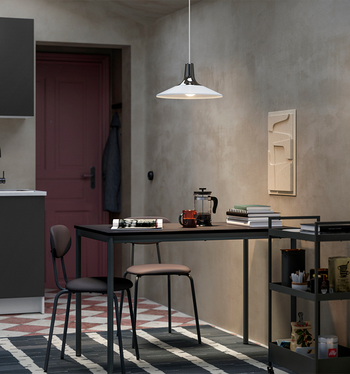 Kitchen or dining area with exposed concrete walls and checkered tile flooring, featuring a dark sink, a cabinet, a burgundy door, and a black dining table with matching chairs, and a metal utility cart with accessories.