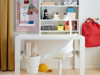 Escritorio IKEA blanco bien organizado con estantes, silla giratoria y mochila, listo para estudiar.