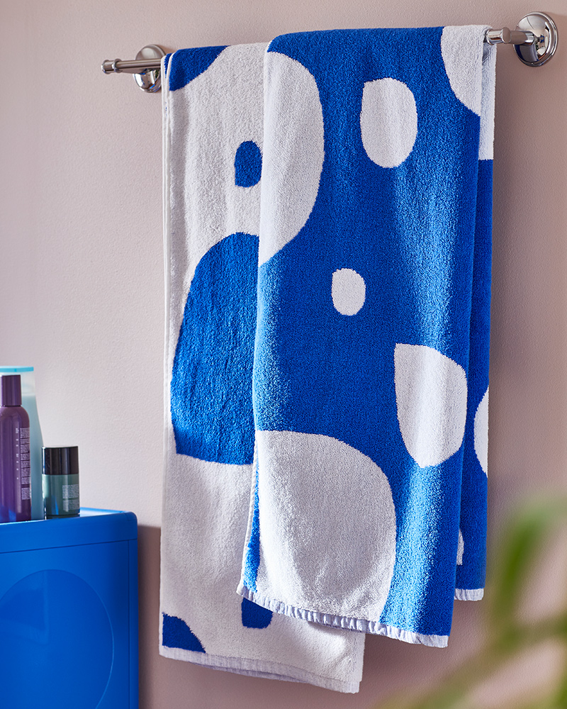 Two blue and white BERGVATTNET bath towels are hanging on a chrome-plated BALUNGEN towel rail on a bathroom wall.
