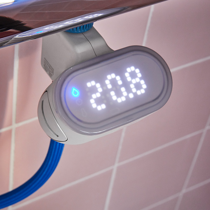 A BERGVATTNET water meter for shower is connected to a thermostatic shower mixer and a blue hose in a tiled shower