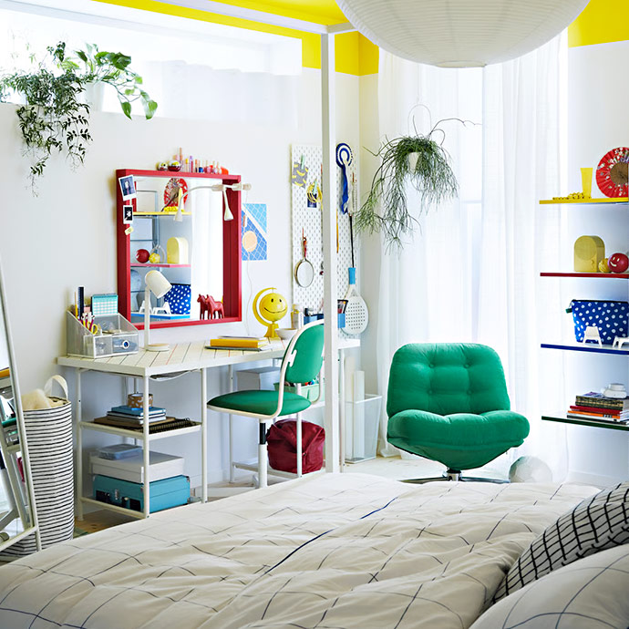 Dormitorio infantil con escritorio blanco y silla verde, sillón verde y cama. Espacio creativo con almacenamiento.