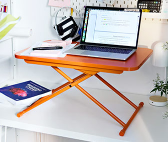 Escritorio elevable plegable naranja para portátil, ideal para trabajar de pie o sentado en espacios pequeños.