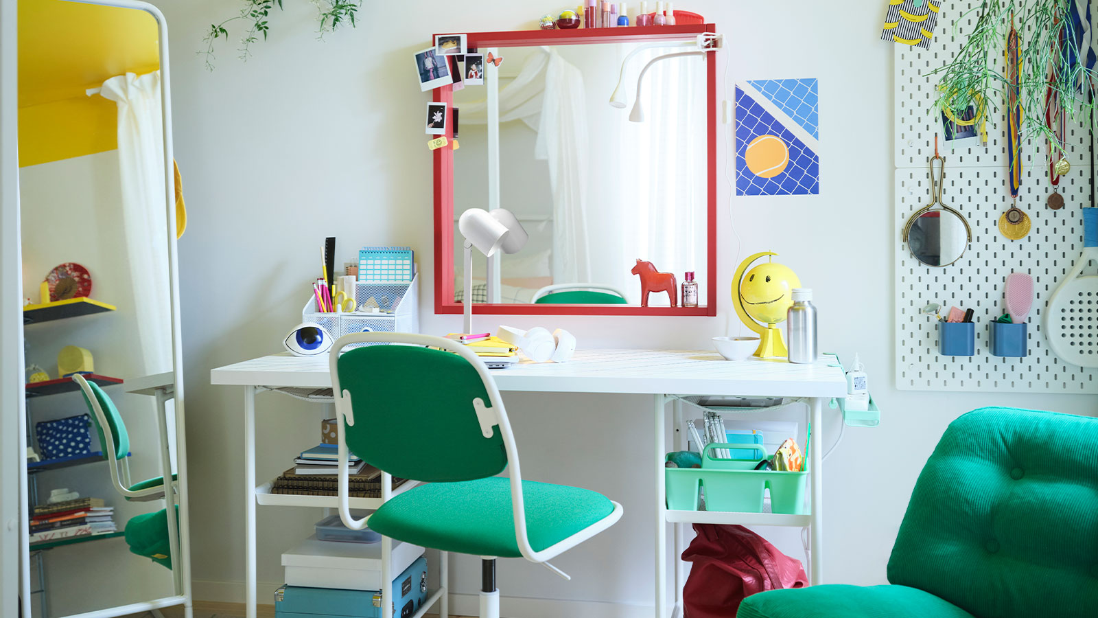 Un dormitorio juvenil con una gran cama blanca, un escritorio con un gran espejo rojo encima, una silla de escritorio y un sillón verdes, y mucho más.
