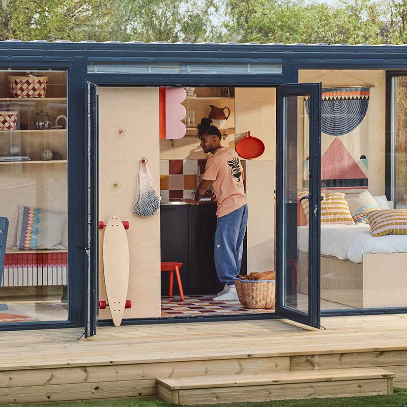 Apartamento hecho con containers, con ventanas al dormitorio y sala; puerta abierta muestra artículos OMMJÄNGE de IKEA
