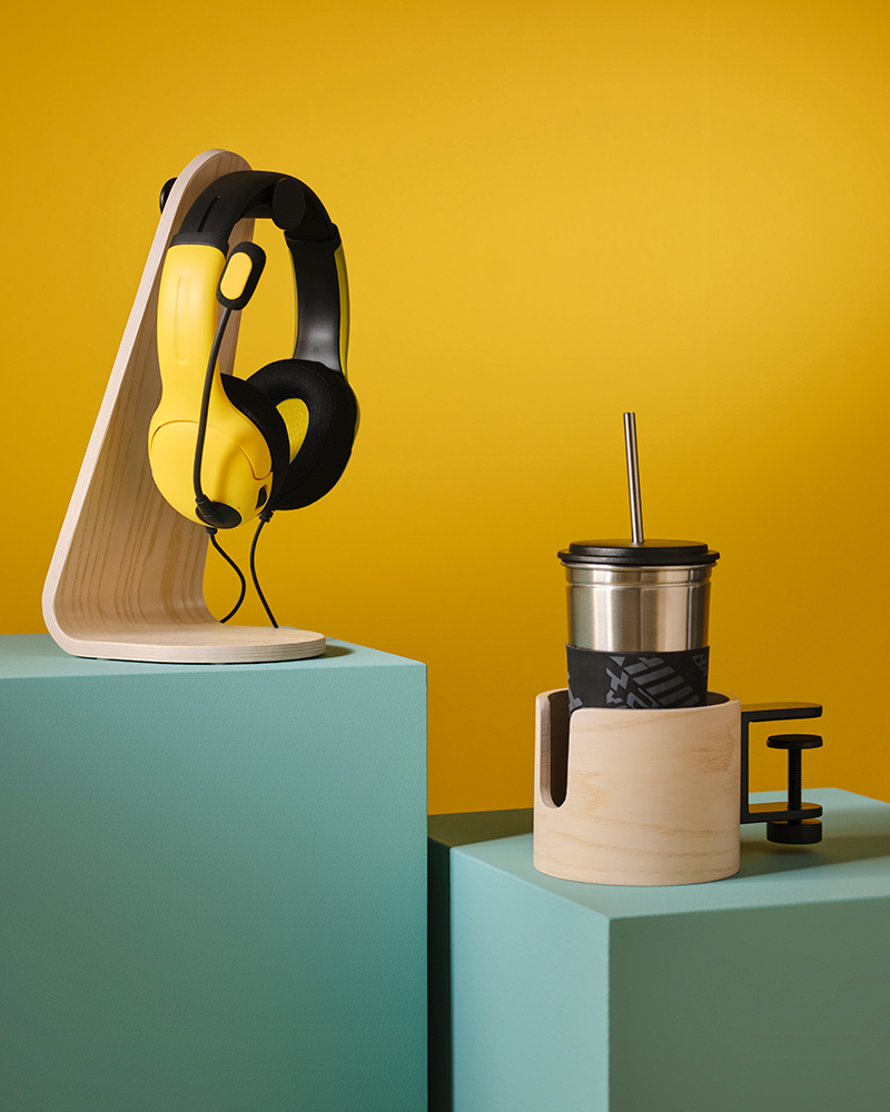 Un par de auriculares y una taza grande colocados sobre soportes de la serie LÅNESPELARE.