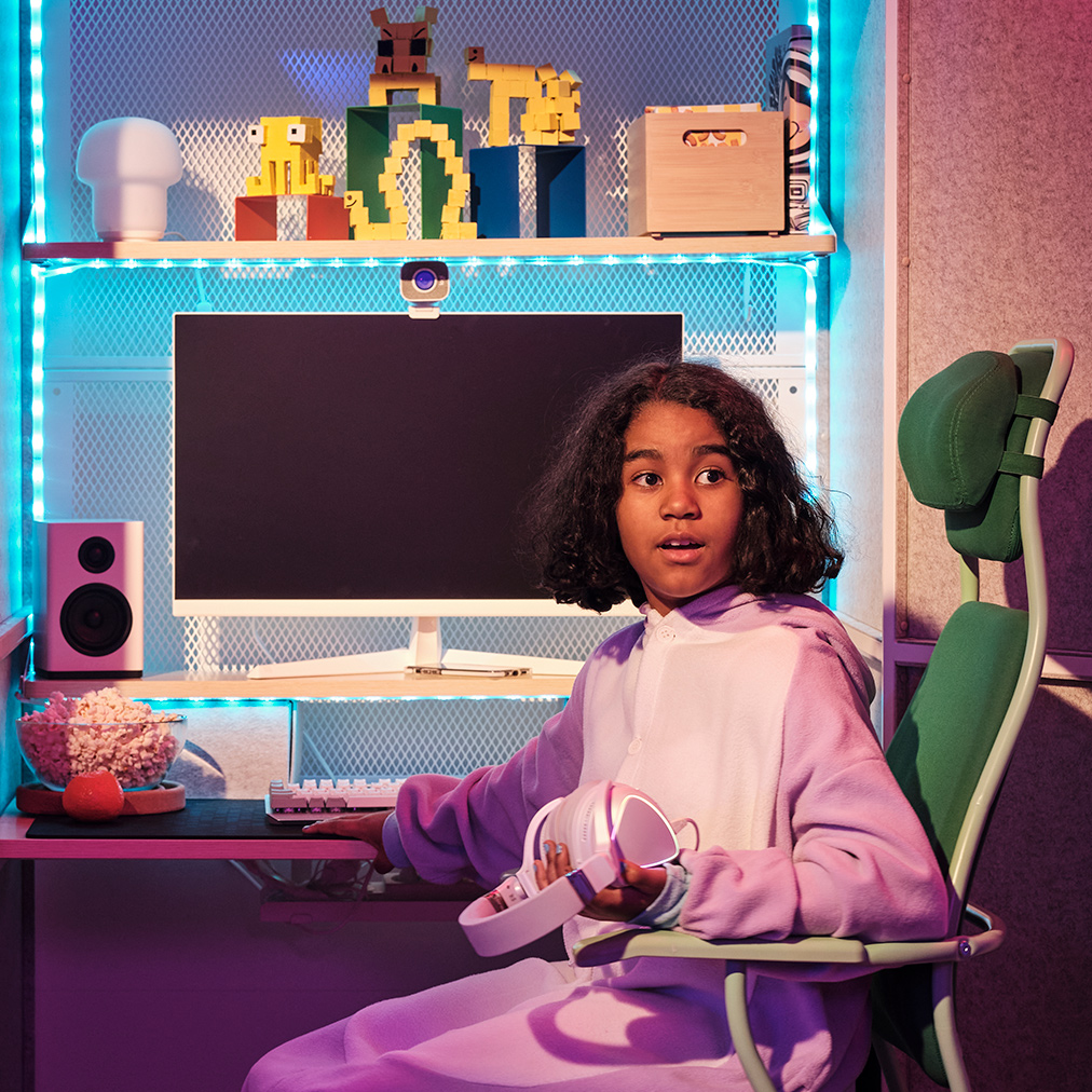 Niña con pijama rosa sentada en una silla verde LÖPARBANA frente a una estación de juego BRÄNNBOLL.