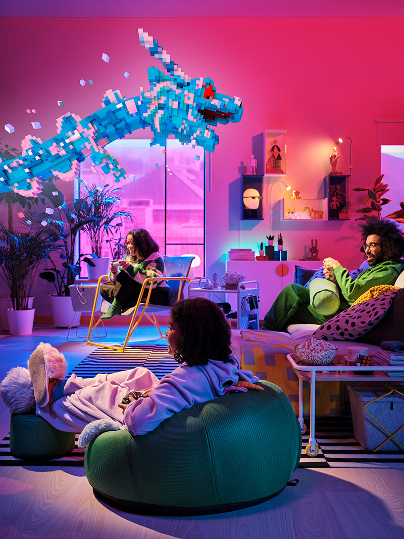 Varias personas jugando en una habitación, una de ellas usando una silla inflable BRÄNNBOLL junto a una mesa auxiliar BRÄNNBOLL, y al fondo una niña en un sofá BRÄNNBOLL junto a un estante rodante BRÄNNBOLL.