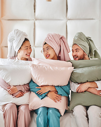 three young people, each holding a pair of pillows