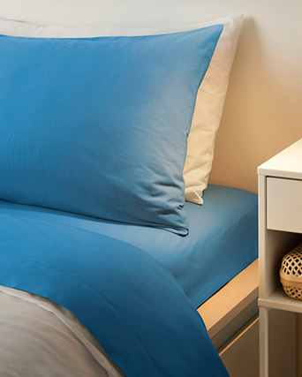 a bed with two pillows, dressed in blue bedding