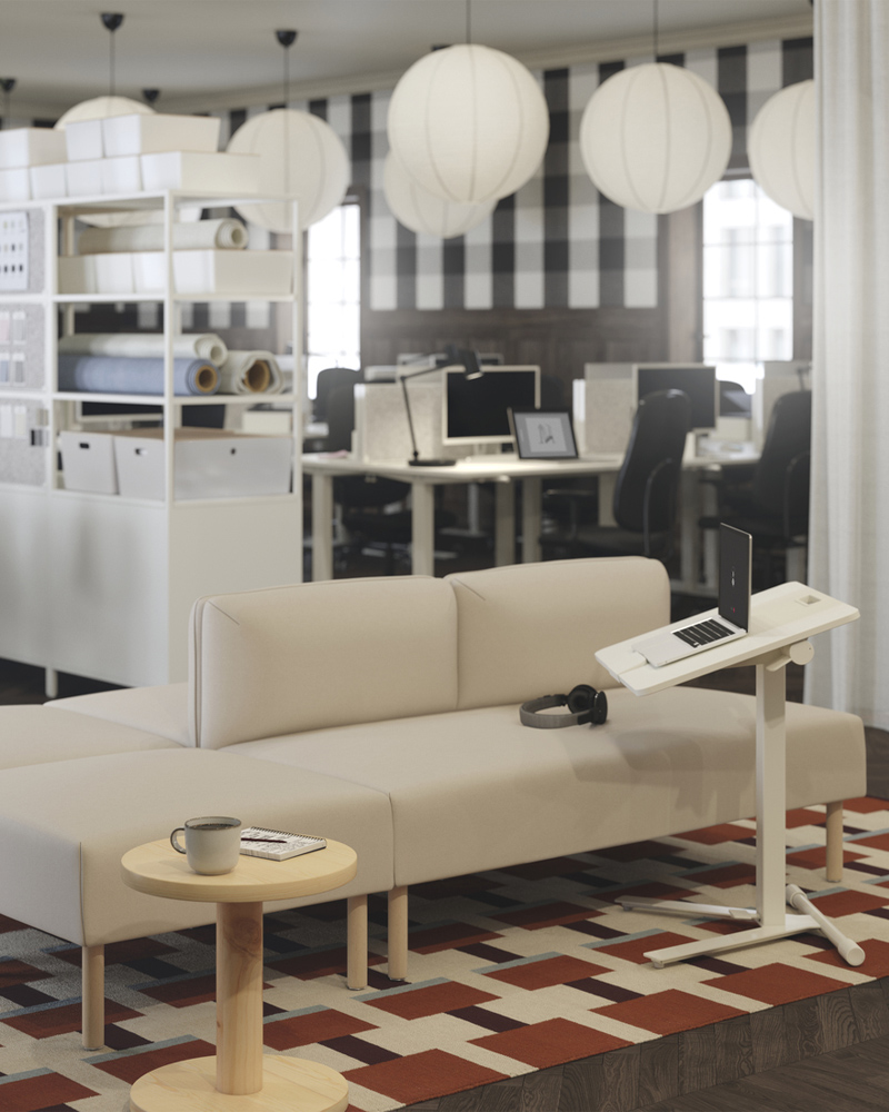 Un sofá modular LILLEHEM beige con patas de madera, combinado con una mesa para portátil MITTZON blanca, sobre una alfombra con estampado geométrico.