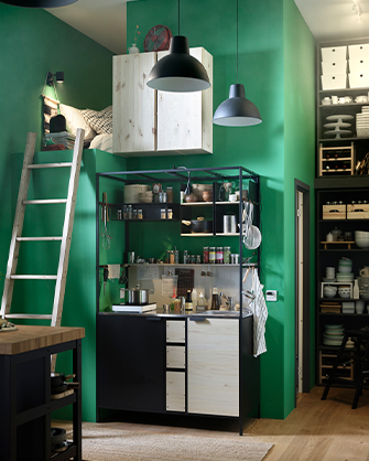 View of a kitchen in a small space with green walls. Includes a loft bed, a modular kitchen unit, and a shelf.