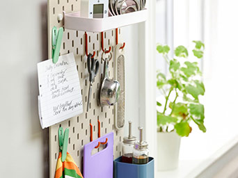 Sistema de almacenaje de pared SKÅDIS, con un listado, tijeras y accesorios de cocina.