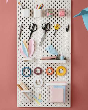 Dos tableros de almacenaje SKÅDIS montados en la pared, con varios accesorios y artículos de manualidades.