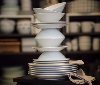 All pieces of a white IKEA 365+ 18-piece service are playfully stacked on top of each other on a black stepladder.