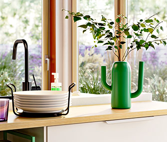 Kitchen counter with a black faucet, stacked plates, and a green cactus-shaped vase.