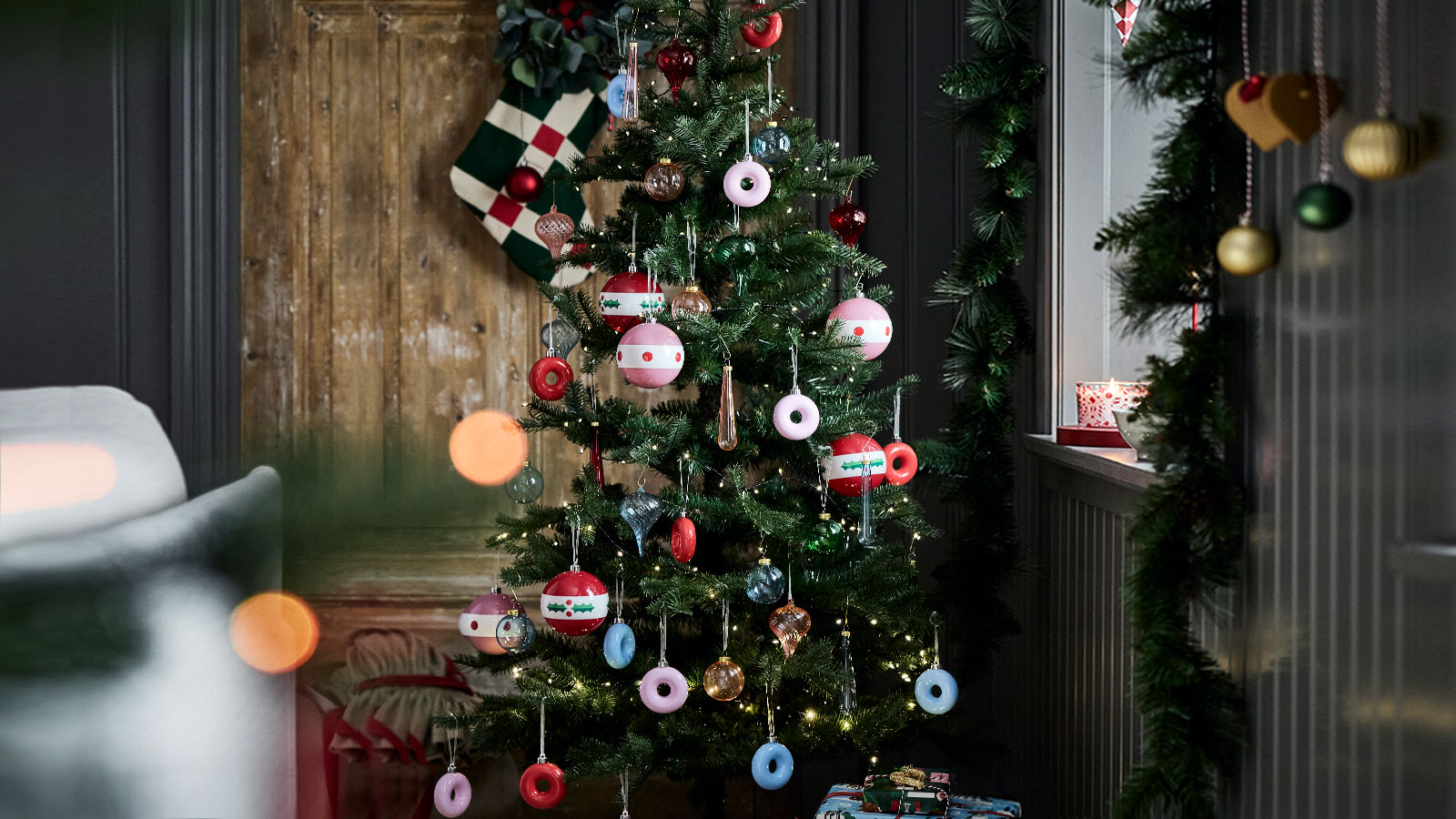 Un árbol de Navidad está decorado con divertidos adornos VINTERFINT con forma de donuts colgados de sus ramas.