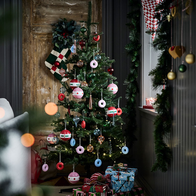 Un árbol de Navidad está decorado con divertidos adornos VINTERFINT con forma de donuts colgados de sus ramas.