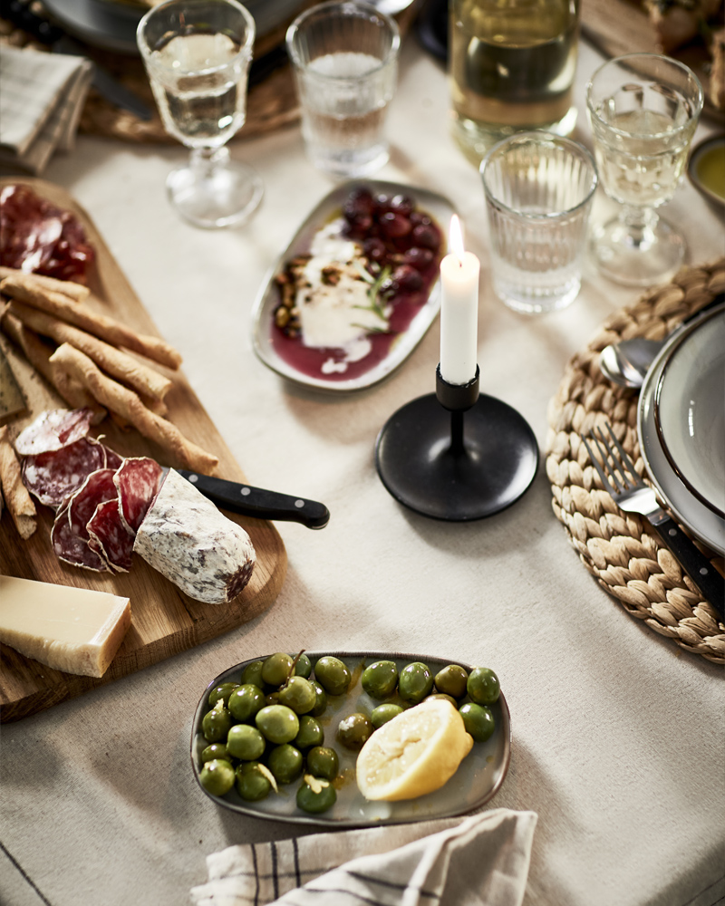 Mesa elegante con aceitunas, quesos, embutidos y copas de vino – ambiente acogedor escandinavo.