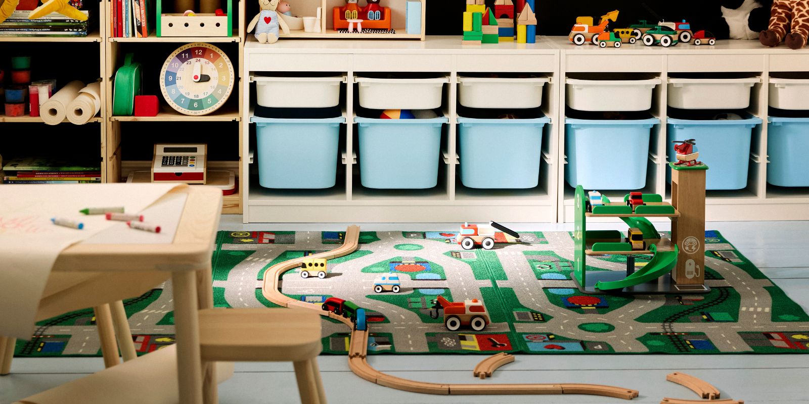Cuarto de juegos infantil colorido con paredes negras, un escritorio de madera clara y almacenamiento. Contenedores azules y blancos.