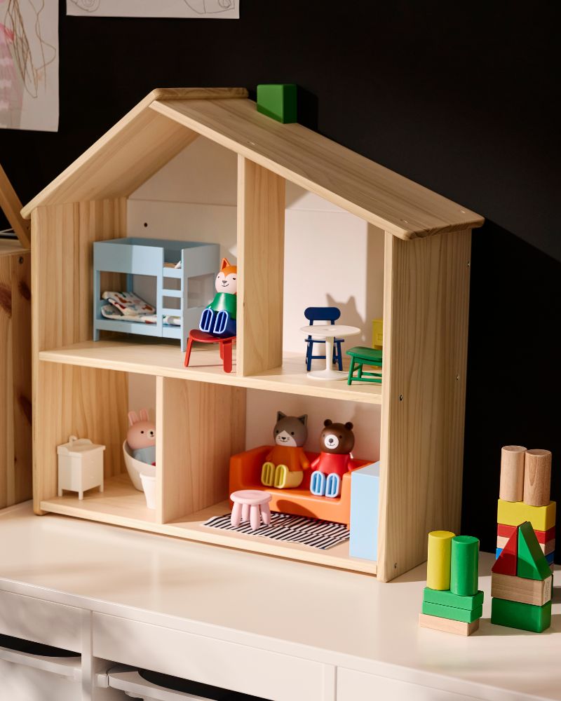 Una casa de muñecas de madera natural con muebles de colores y figuras de animales, que incluye una litera azul y un sofá naranja.