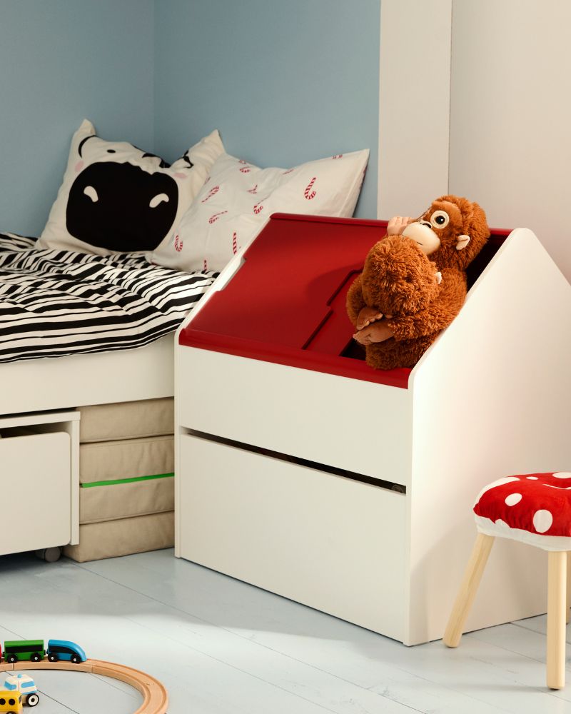 Dormitorio infantil con cama blanca, ropa de cama a rayas, juguetes de peluche y pared azul.