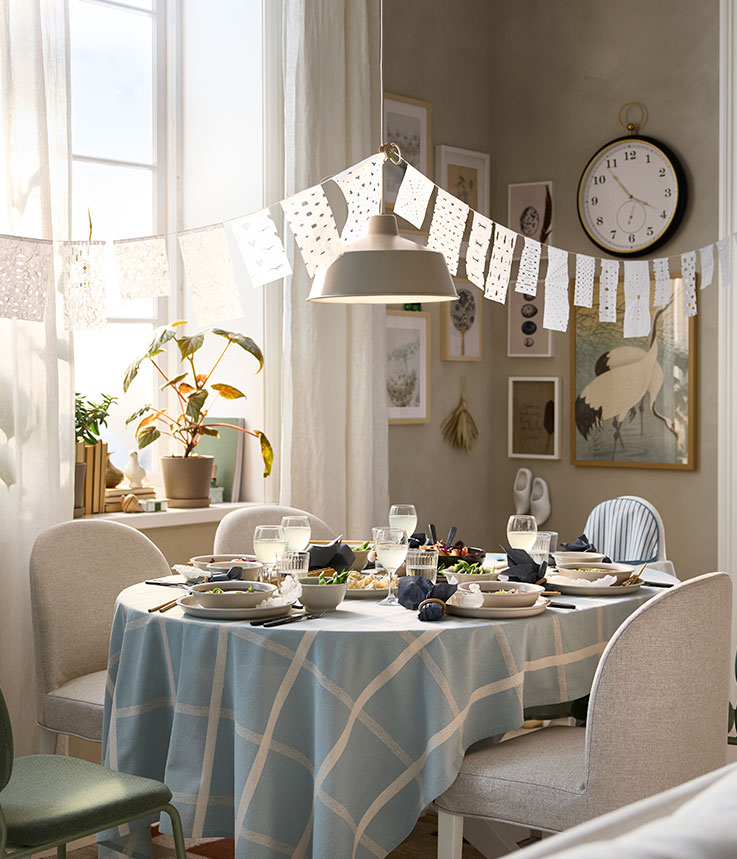 A bright dining room has a ROSENTORP extendable table that has been pulled out to accommodate five chairs and one highchair.