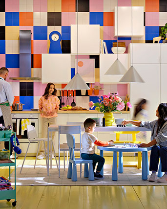 Colorful kitchen with people cooking, playing and chatting.