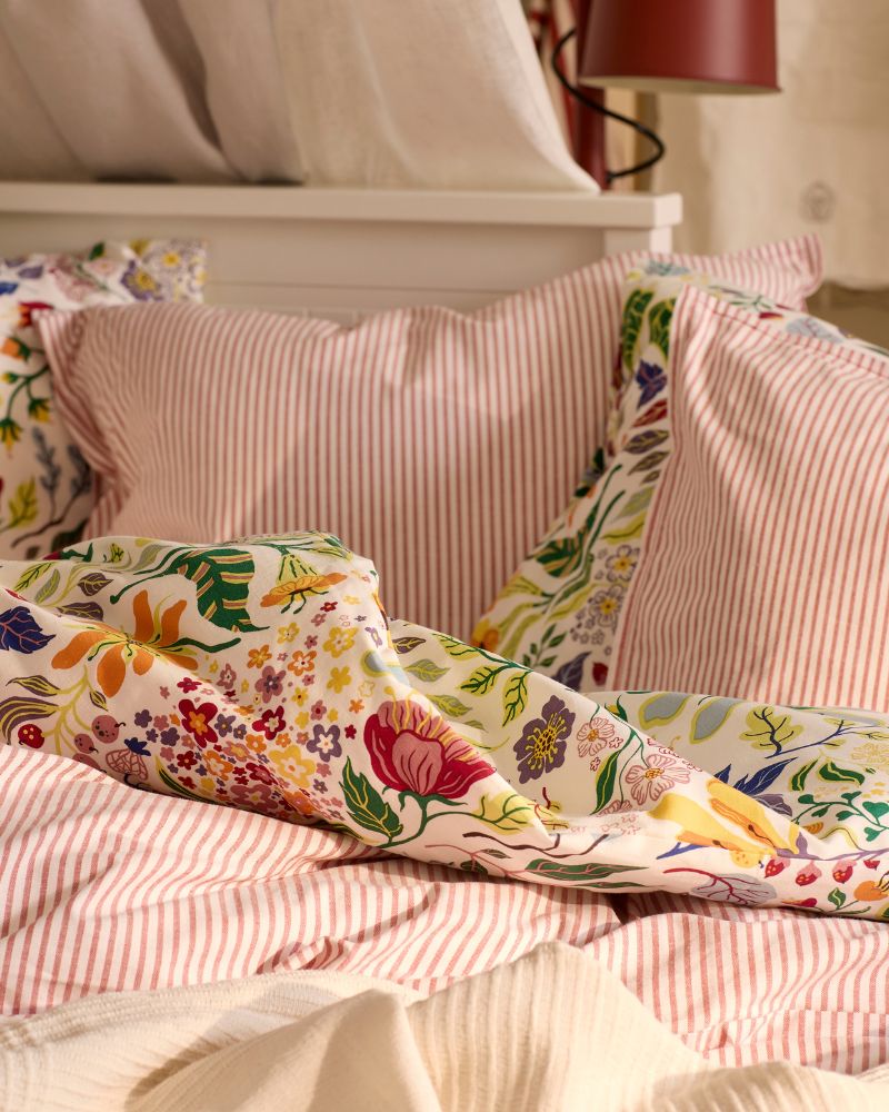 A close-up of a HEMNES day-bed with a mix of bedlinen; the striped SOLFIBBLA and the oral patterned BRUDKRUSBÄR.