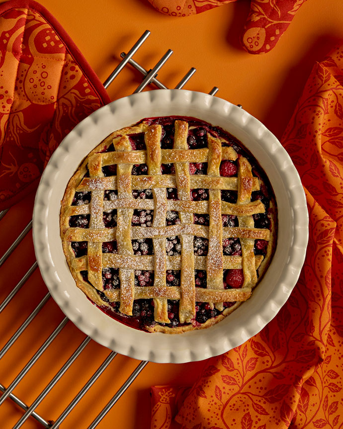Tarta de frutos rojos con azúcar glas. Paños naranjas decorativos.