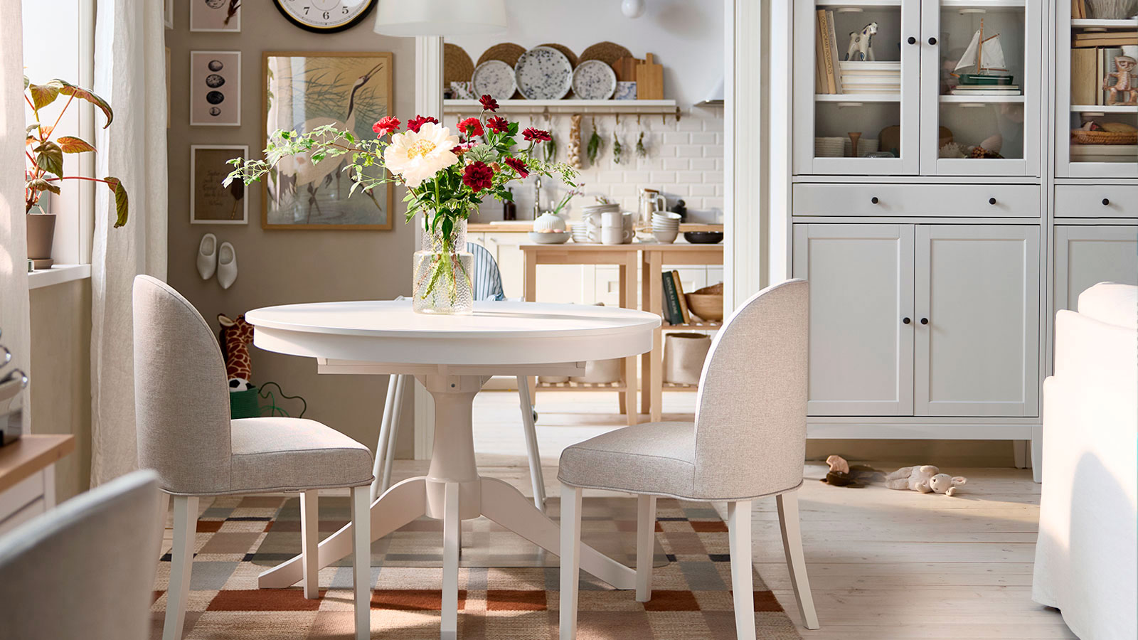 A bright dining area has a white ROSENTORP extendable table, two ROSENTORP chairs and an ANTILOP highchair with tray.