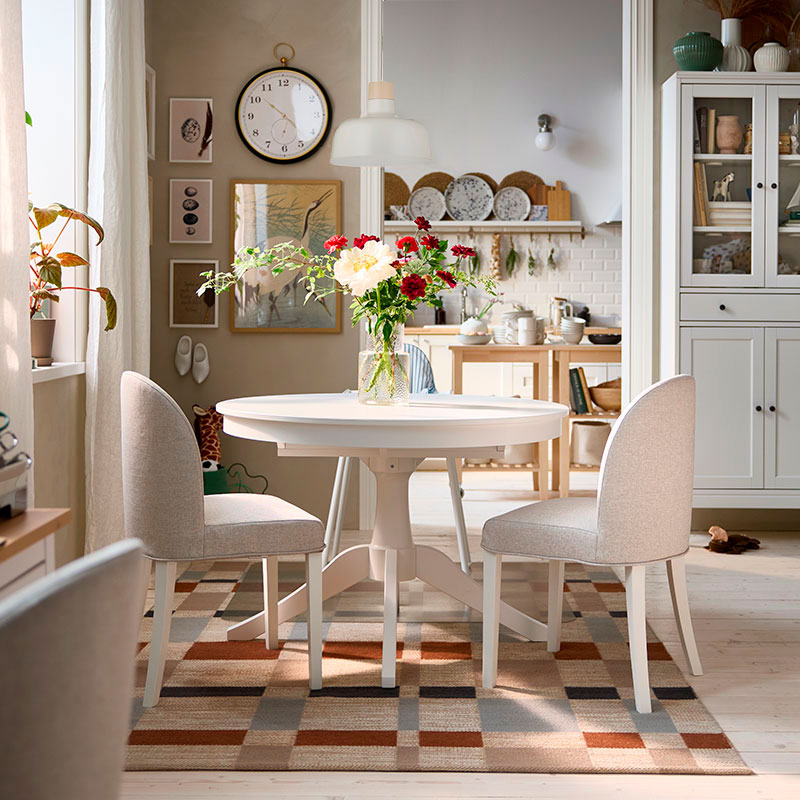 A bright dining area has a white ROSENTORP extendable table, two ROSENTORP chairs and an ANTILOP highchair with tray.