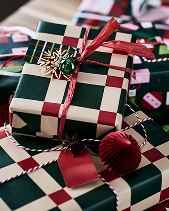 Los regalos de Navidad están envueltos de forma festiva con papel de regalo VINTERFINT, con un llamativo diseño a cuadros verdes y rojos.