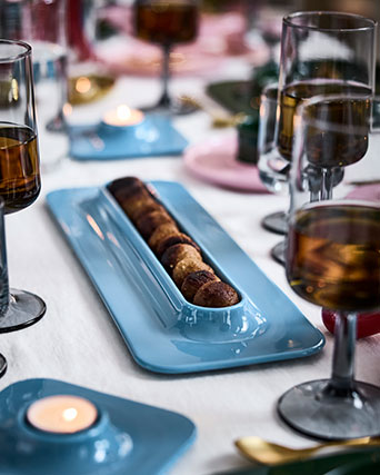 Una fila de albóndigas se encuentra en un plato azul VINTERFINT, sobre una mesa decorada de forma festiva.