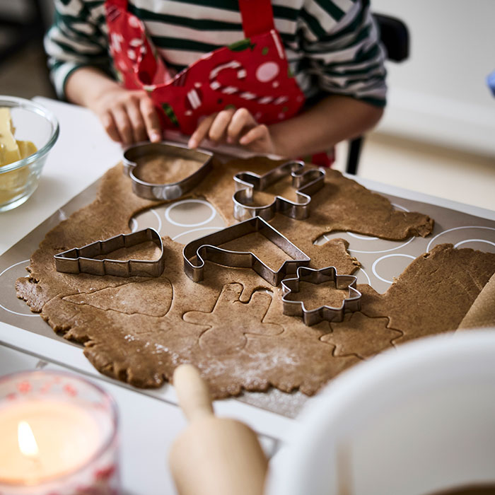Un niño está utilizando cortadores de galletas VINTERFINT para dar formas festivas a una masa de jengibre aplanada.
