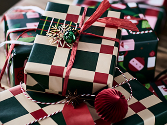 Montón de regalos envueltos con papel a cuadros verdes, blancos y rojos. El regalo superior está atado con una cinta roja.